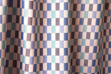 Beautiful nude checkered fabric texture with folds and contrasting shadows. Draped background of...