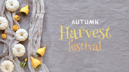 Autumn harvest festival text with natural pumpkins and quince fruit. Flat lay, top view on grey...