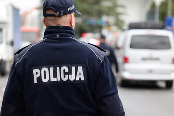 Polscy policjanci w niebieskim mundurze na zabezpieczeniu imprezy w mieście.