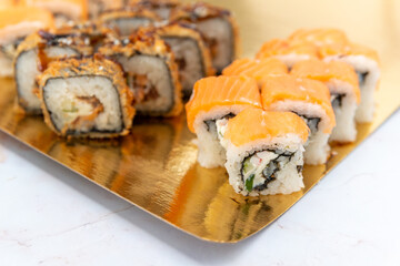 sushi rolls on a gold plate on a white background