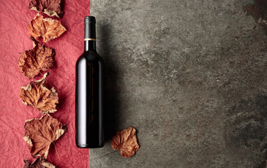 Bottle of red wine with dried vine leaves.