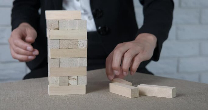 Businessman with construction blocks. A man makes a layout with wooden small blocks on the office table.