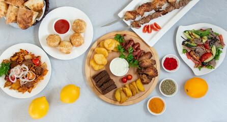 oriental cuisine, barbecue, manti, sausage snacks, salad, fried potatoes on a white table decorated with spices and lemons