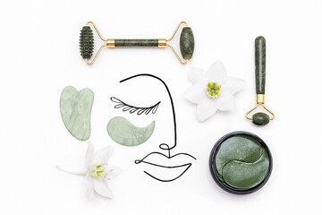 Creative modern selfcare concept. Surreal woman face and set of cosmetic tools for self-care. Face rollers, massager gua sha scraper, cosmetic collagen patches on white background. Flat lay