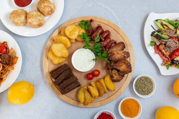 oriental cuisine, barbecue, manti, sausage snacks, salad, fried potatoes on a white table decorated with spices and lemons