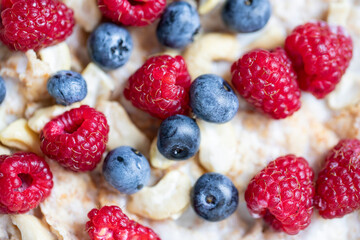 Whole grain oat flakes with fresh ripe blueberries, raspberries, yogurt and vegan almond milk close up. Healthy breakfast concept	