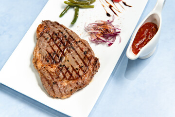 beef steak on a square white plate on a blue sky background close up