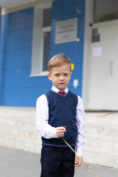 Cute Boy First Grader At School With A Balloon In His Hand On A Sunny Autumn Day. Celebration On September 1st. Knowledge Day. Selective Focus