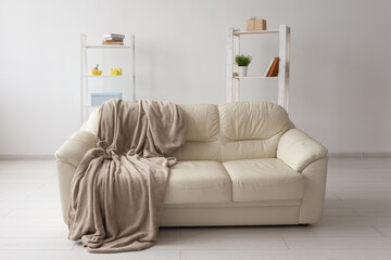 Beige sofa against white empty wall in simple living room interior. Minimalism concept.