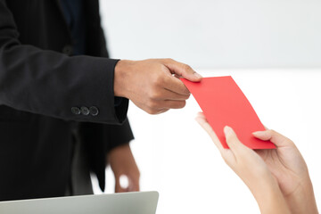 boss or manager hands giving cash bonus in red envelope to employee in meeting room