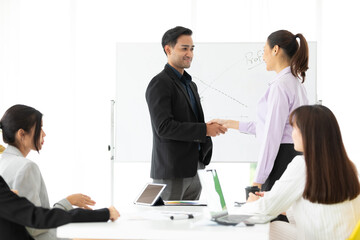 businesswoman and businessman  shaking hands together with partners for a job in conference room