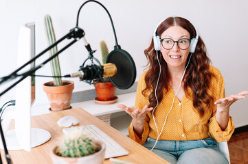 Woman with microphone and headphones talking and recording podcast at studio