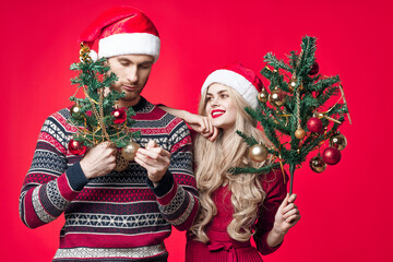 cheerful young couple in new year clothes decoration toys red background