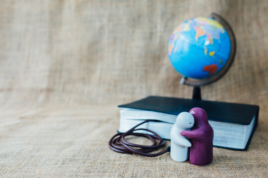  two ceramic people model hugging together  with cable that connect  to the holy bible on linen sackcloth over world globe,  Christian conceptual image show word of God is power of Christian life 