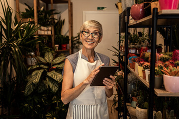 Portrait of senior female florist working in her flower shop.