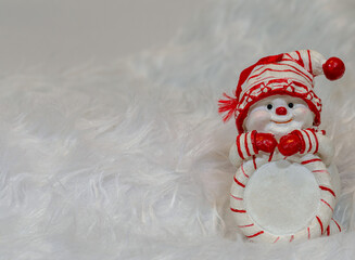 White Christmas background with a snowman wearing a red and white hat and scarf. copy space