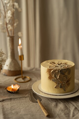 beautiful composition of flowers in a handmade vase and candles, on a handmade wooden table with delicious handmade sponge cake