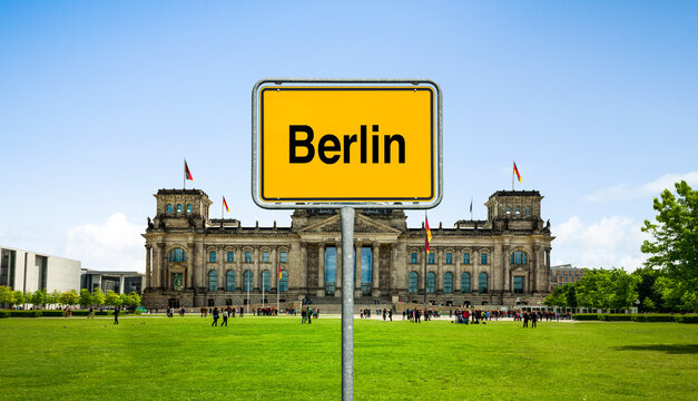 Wiese vor dem Reichstagsgeb&auml;ude mit einem Ortsschild Berlin, Deutschland