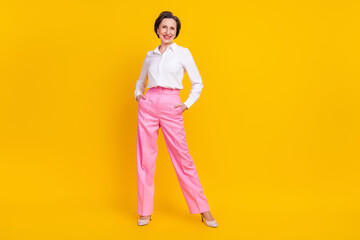 Fototapeta premium Photo of sweet confident mature lady wear white clothes smiling standing arms pockets isolated yellow color background
