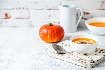 Pumpkin cream soup in white bowl copy space