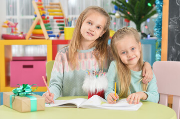 Portrait of cute sisters drawing with pencils