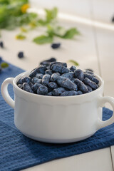 honeysuckle in a white cup stands on a blue napkin. greenery in the background. vertical frame.