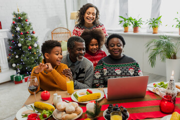 happy african american family having video call during christmas dinner