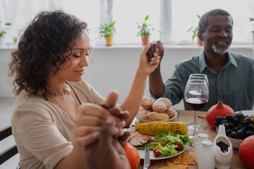 african american woman holding hands with parents while praying before thanksgiving dinner with closed eyes
