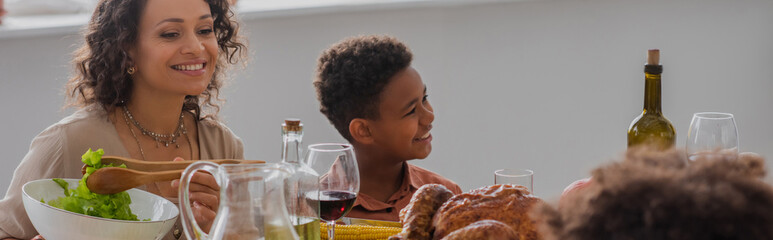 African american mother and son sitting near thanksgiving dinner, banner