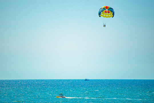 A parachute on a rope flies in the blue sky behind the boat. Beach Parachute