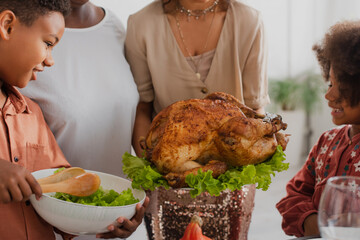 African american kids standing near mother with tasty turkey during thanksgiving