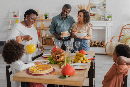 Smiling African American Family Serving Thanksgiving Dinner Near Blurred Kids