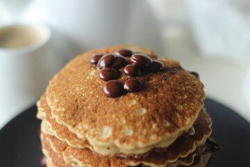 Stack of Oats Choco chips pancakes along with coffee for breakfast. Healthy pancakes made of oats flour loaded with chocolate chips