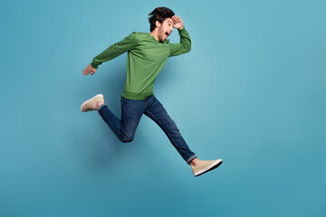 Obraz premium Full size profile photo of funky funny man running in air look copyspace watch forward ahead isolated on blue color background
