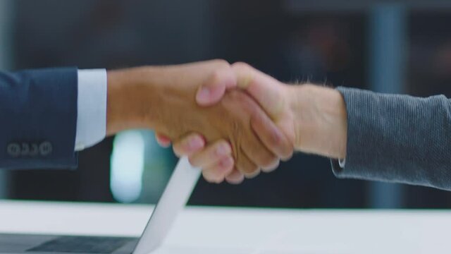 Close-up footage of handshaking. Males shake hands as proof of their agreement. Modern open space office interior.