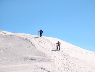 Fototapeta na wymiar Two Hikers on a trail walking through snow. Winter landscape in Carapathian Mountains, Romania.