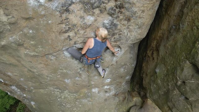 Strong Senior Female Climber Climbing Steep Wall Of Rocky Mountain. Sportswoman Overcoming Difficult Route. Engaging In Extreme Sports Hobby Concept.