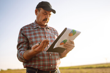 Farmer watching some charts and checks quality of soil. Agriculture, gardening, business or ecology concept.