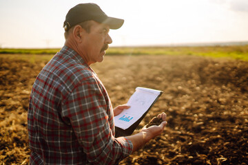 Farmer watching some charts and checks quality of soil. Agriculture, gardening, business or ecology concept.