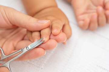 Obraz na płótnie Canvas Baby nail cut. Hand with scissors trims the fingernails of the sleeping baby. Selective focus