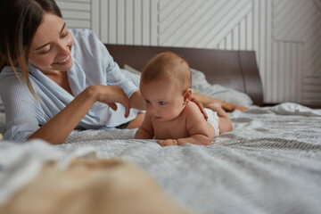 Mother giving opportunity for baby to crowl on bed