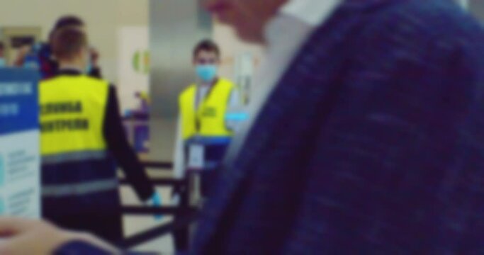 modern city life. several security workers are checking people. blurry defocused video. silhouettes of unrecognizable people in a large bright hall.