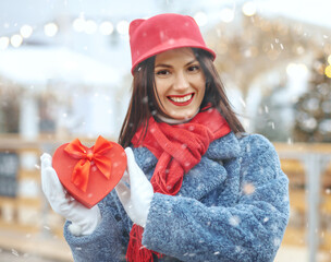 Emotional lady holding a gift box at new year fair during the snowfall