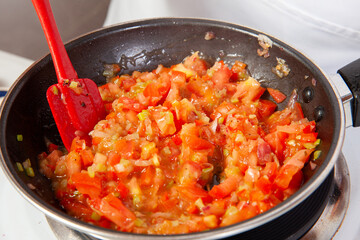 Preparation of the traditional Colombian hogao or criollo sauce (salsa criolla) made of onion, tomato, peppers and cilantro
