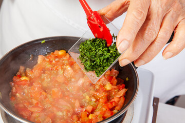 Preparation of the traditional Colombian hogao or criollo sauce (salsa criolla) made of onion, tomato, peppers and cilantro
