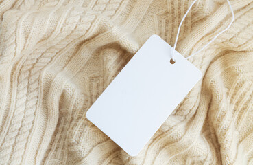 Mock-up of blank white paper price tag or label on sweater background