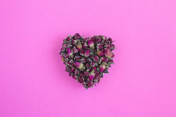 Close-up on dried roses in the form of a heart on the pink  background