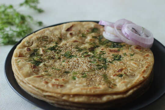 Perfectly round Paratha. Indian flatbread made of wheat flour topped with sesame seeds and coriander leaves