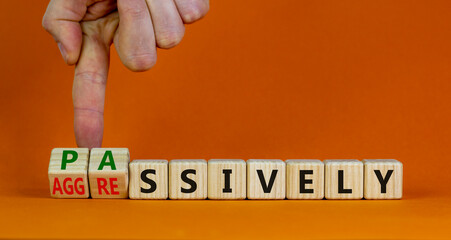 Passively or aggressively symbol. Businessman turns cubes and changes the word passively to aggressively. Psychological and passively or aggressively concept. Beautiful orange background, copy space.