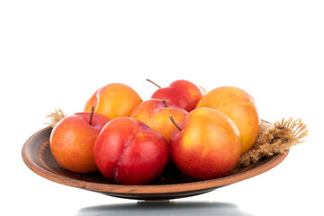 Several juicy organic yellow-red plums on a ceramic plate, close-up, isolated on white.